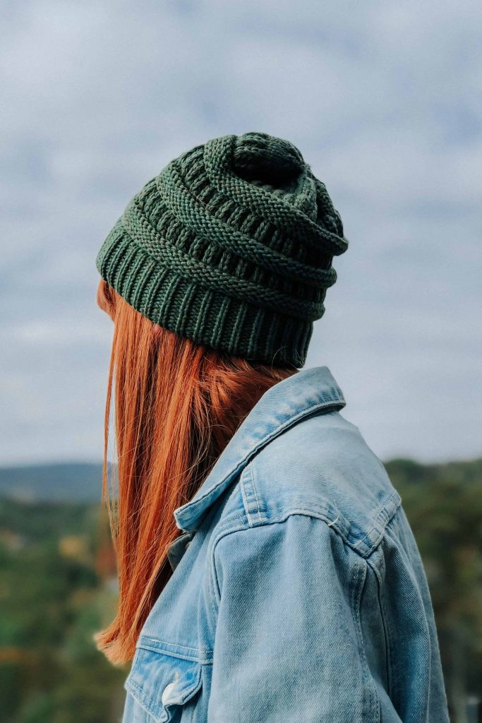 A photo of a girl with red hair wearing a green hat